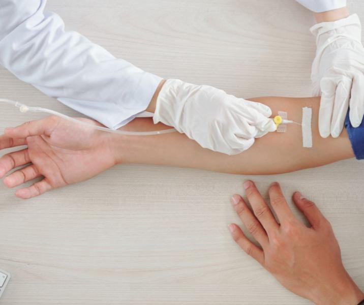 Healthcare professional performing pathology blood collection from patient's arm using sterile technique