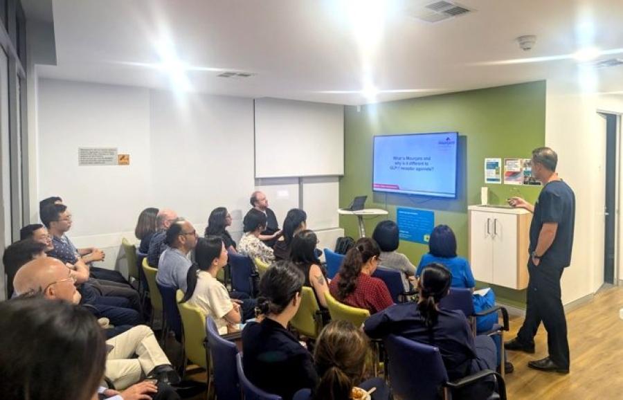 Doctor presenting to seated attendees at a medical education event in a clinic meeting room
