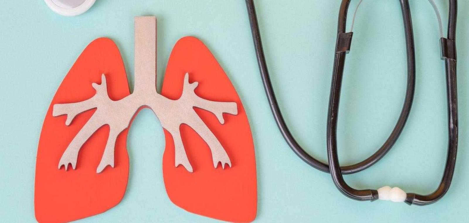 Paper lung illustration beside a stethoscope on a blue background