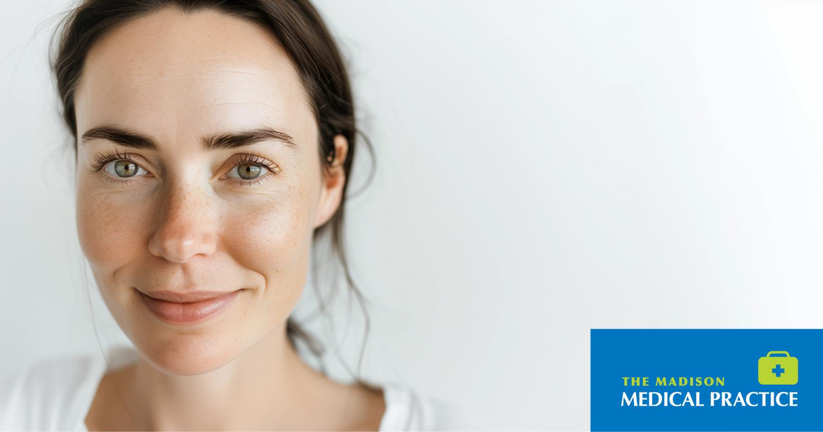 Close-up portrait of a smiling woman with clear skin against a light background