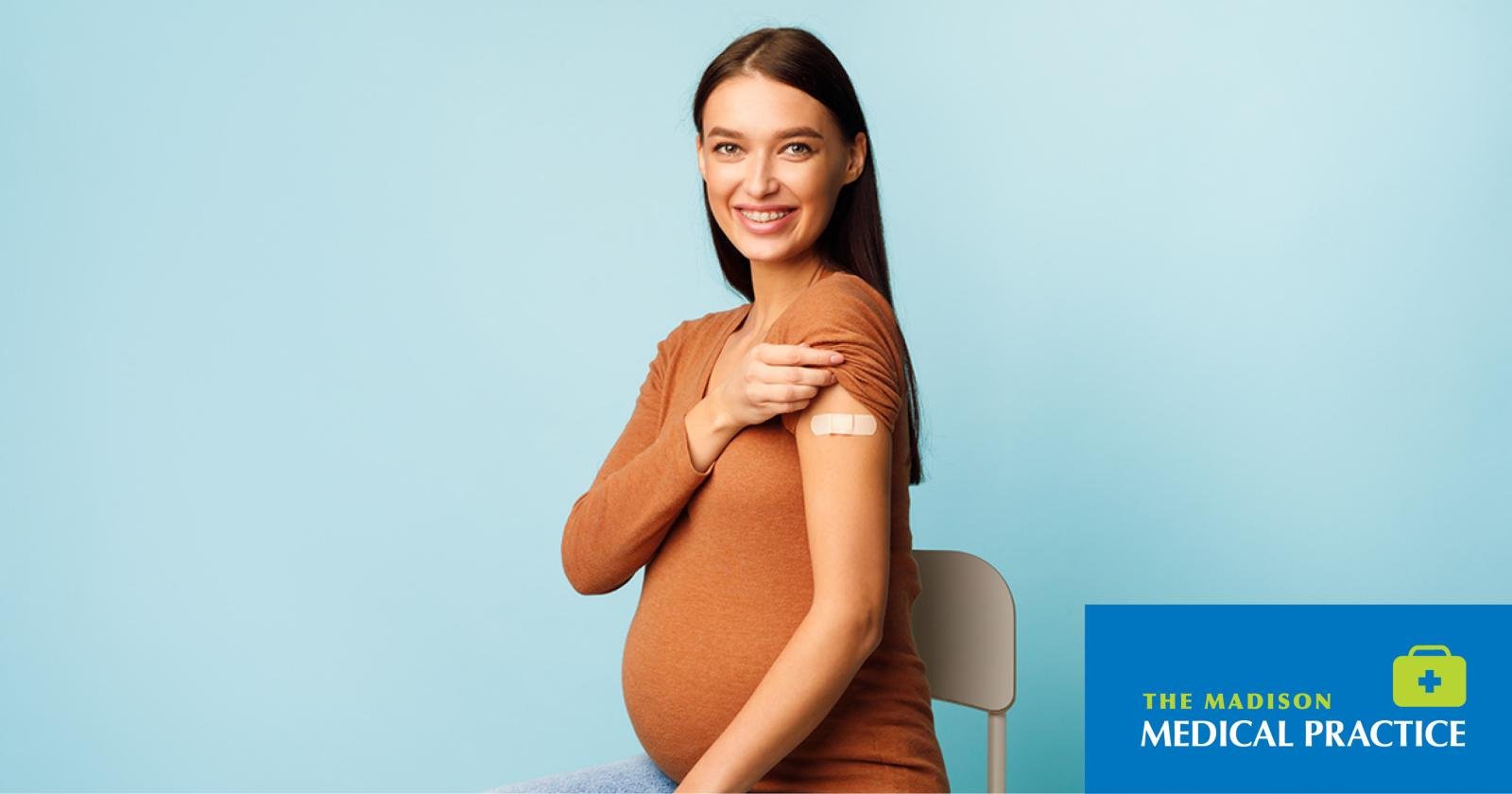 Pregnant woman smiling with a bandage on her upper arm after vaccination