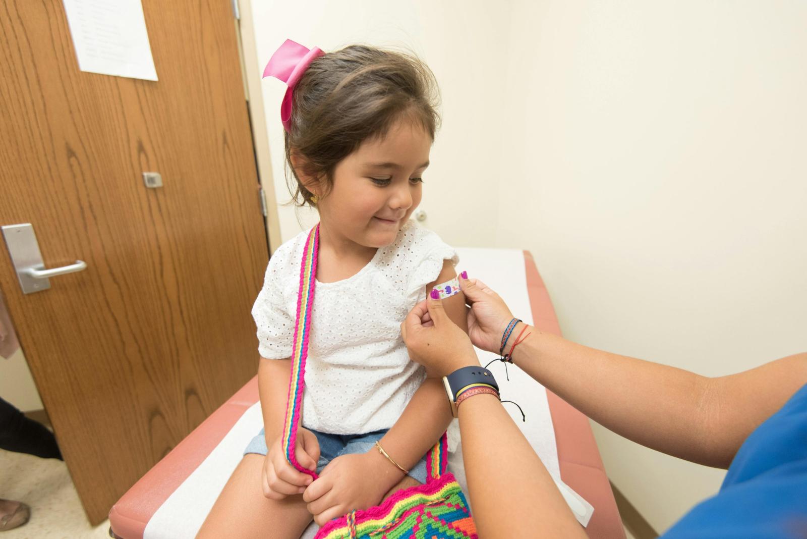 Child having a medical ear piercing in a clinic consultation room