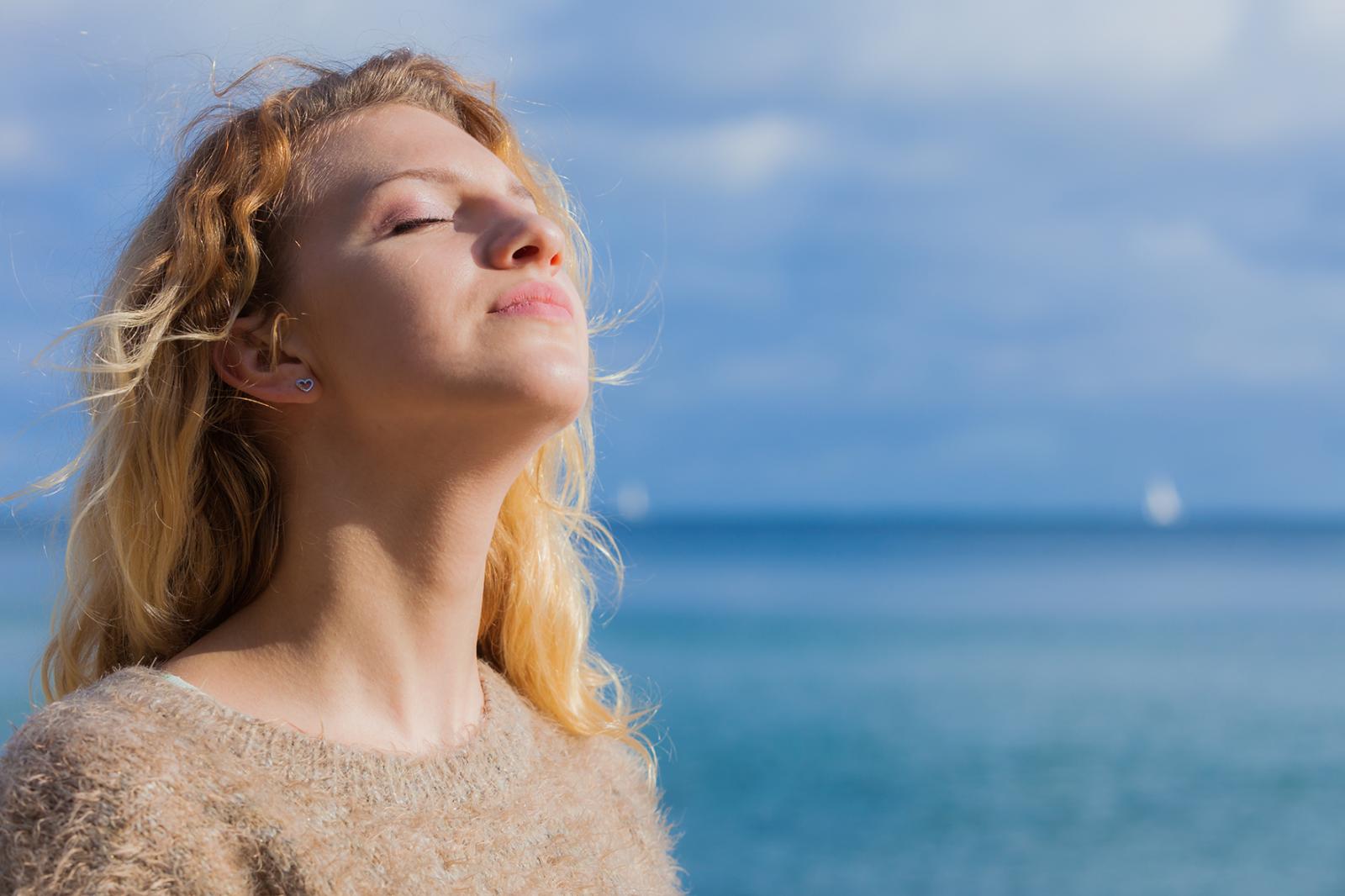 Woman enjoying sunlight by the sea, highlighting sun exposure and skin health