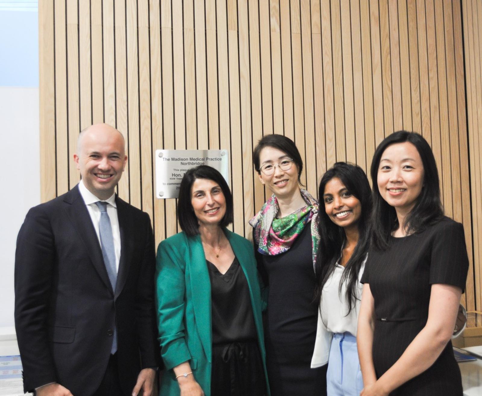 Five healthcare professionals standing together in a clinic reception area