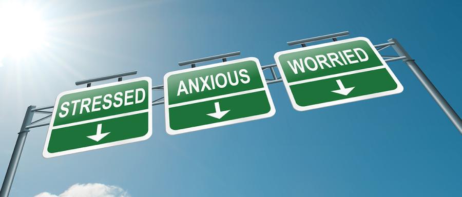 Three road signs reading stressed, anxious and worried against a clear blue sky