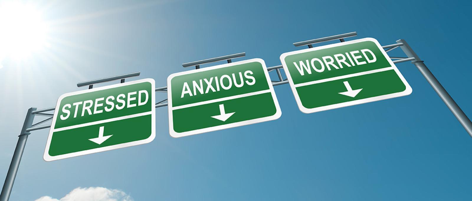 Three road signs reading stressed, anxious and worried against a clear blue sky