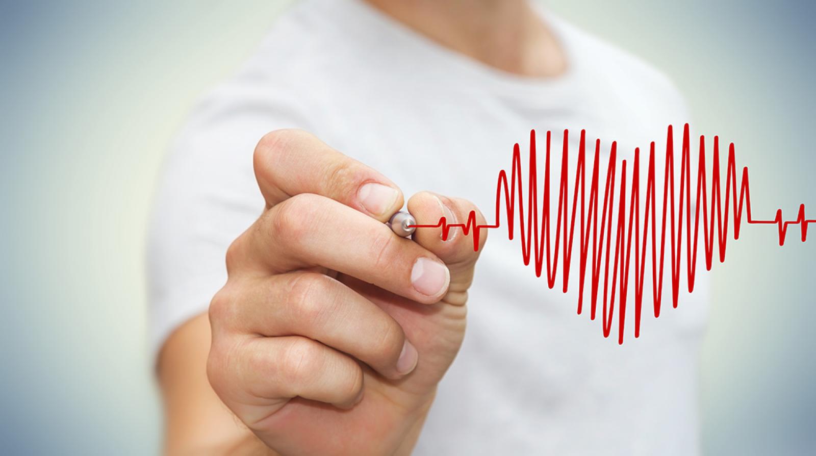Person drawing a red heart rhythm line symbolising cardiovascular health