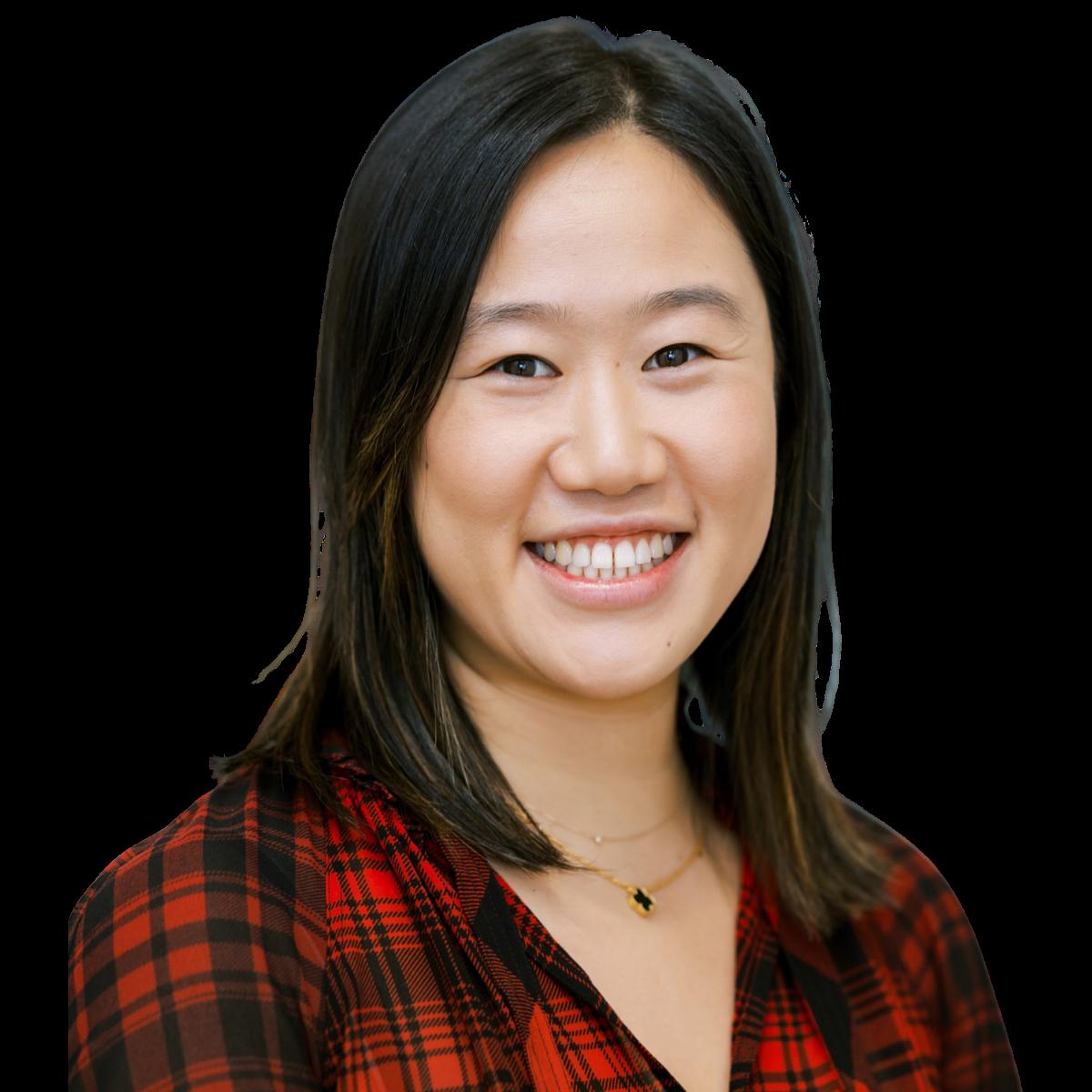 Professional headshot of a smiling female doctor in a red check shirt