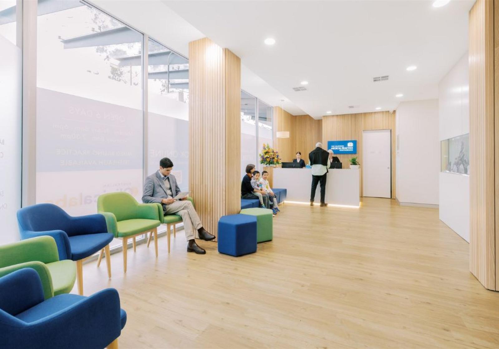 Modern medical practice waiting room with reception desk and seated patients